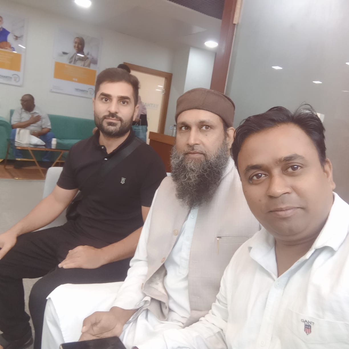 Three men seated side by side in a waiting lounge